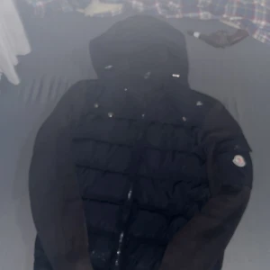 Svart Moncler pufferjacka med huva - Säljer en svart pufferjacka från Moncler med huva och dragkedja. Jackan har quiltad front, släta ärmar och Moncler-logga på ena ärmen. Perfekt för kalla dagar och riktigt snygg streetstil. Det går att förhandla. Jag vill bara bli av med den