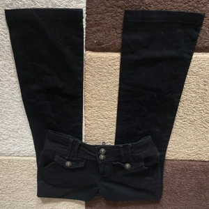Svarta utsvängda jeans från Next - Snygga svarta utsvängda jeans från Next i storlek S. Perfekta för en trendig look med sina vida ben och klassiska design. Midjemått är 36 cm och innerbenslängd 77 cm.