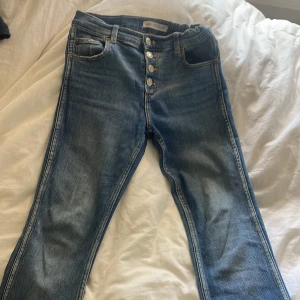 Blå jeans med knappar från Zara - Snygga blå jeans från Zara med raka ben och klassisk femficksmodell. Aldrig använt. Dom är ganska low waist.