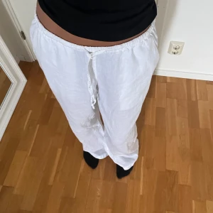Vita linnebyxor från Gina Tricot - Säljer ett par vita linnebyxor från Gina Tricot i storlek S. Byxorna har rak passform, resår i midjan och snörning framtill. Perfekta för varma dagar med sitt luftiga material och stilrena look.