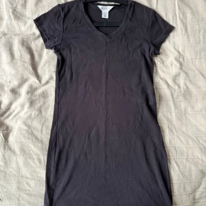 Svart knälång t-shirtklänning - Svart t-shirtklänning i mjuk bomull. Casual, stilren, höstig och så bekväm! Tror att den är lite solblekt i vissa partier (så som det ser ut på bilden) men i verkligheten  märks detta knappt, säljer den dock väldigt billigt av den anledningen👏🫶