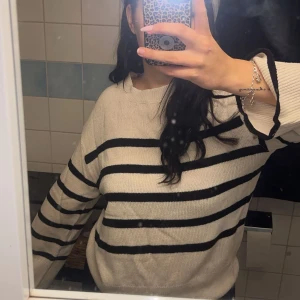 Randig beige tröja från Vero Moda - Säljer en snygg beige stickad tröja från HM i storlek S. Tröjan har svarta horisontella ränder och rund hals. Den är långärmad och har en chill, normal passform som funkar perfekt till jeans eller kjol. Superenkel att styla och passar dig som gillar klassiska mönster.