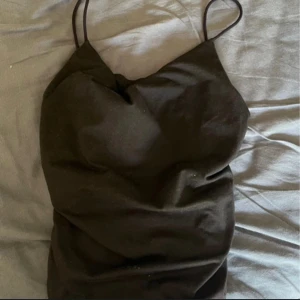 Svart linne med tunna band - Säljer en svart kort klänning med tunna axelband och enkel, stilren design. Perfekt för dig som gillar minimalistiskt och tidlöst mode. Klänningen har en smickrande passform och är lätt att styla med accessoarer.