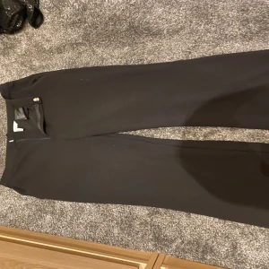 Svarta kostymbyxor i XS - Säljer ett par svarta kostymbyxor i storlek XS. Byxorna har en klassisk rak passform och är tillverkade i ett mjukt material som känns bekvämt hela dagen. Perfekta för en clean och stilren look.