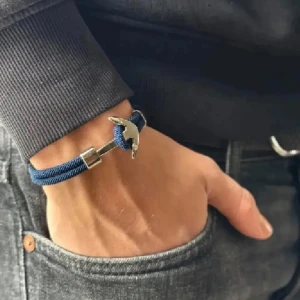 Blått armband med ankare - Snyggt armband i marinblått rep med ett silverfärgat ankare som lås. Armbandet har en enkel och stilren design som passar perfekt till vardagslooken. Repbandet är tvinnat och går att vira två varv runt handleden för en cool effekt.