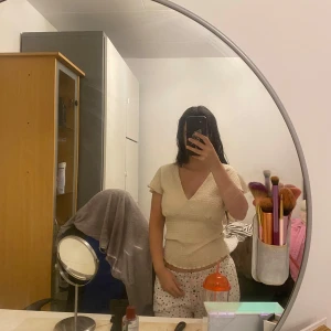 Beige omlottopp från newyorker - Säljer en beige omlottopp från Amisu med v-ringning och korta ärmar. Toppen har en smockad, stretchig struktur som sitter snyggt och bekvämt. Perfekt för dig som gillar en enkel men trendig stil. Passar mig som har xs/s.