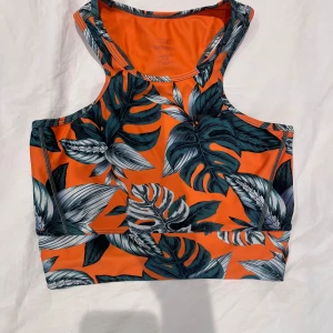 Orange mönstrat träningsset med gröna blad - Säljer ett par riktigt snyggt träningsset med tropiskt print i grönt. De är tillverkade i ett stretchigt material. Midjan är normal och passformen är tight.