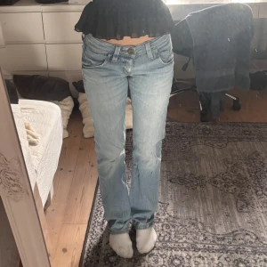 Ljusblå bootcut jeans låg midja - Säljer ett par ljusblå jeans med bootcut och låg midja. Jeansen har klassisk femficksdesign, snygga slitningar och raka ben med lätt utsvängd passform. Perfekta för dig som gillar en avslappnad och trendig look. Slitna nere vid fötterna.