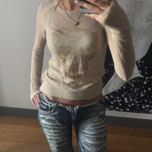 Beige Kashmir  tröja med döskalle Zadig o Voltaire  - Säljer en tunn, beige stickad kashmir tröja med lång ärm och ett coolt döskalletryck i guld på bröstet. Tröjan har en tight passform och är perfekt för dig som gillar edgy detaljer och vill sticka ut lite extra. En lagning på armen som knappt syns. 