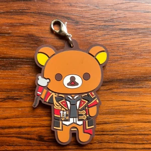 Nyckelring med Rilakkuma-björn - Söt nyckelring i form av Rilakkuma klädd i färgglad jacka med detaljer i rött, svart och guld.  Fungerar bra som nyckelring eller accessoar på väska. Köparen står själv för frakten. Skicka ett meddelande vid intresse. Klicka INTE på ”köp nu”!! 