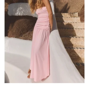 Ljusrosa axelbandslös långklänning - SLUTSÅLD!! Helt oanvänd superfin ljusrosa långklänning med axelbandslös design och rynkade detaljer upptill. Klänningen har en flowy kjol och sitter snyggt över kroppen.❤️