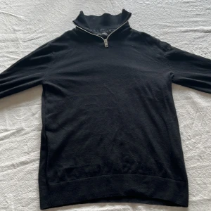 Svart half zip polotröja Jack & Jones - Svart tröja från Jack & Jones med half zip-dragkedja vid halsen. Tröjan är långärmad och har en clean, stilren look. Perfekt för lager-på-lager och funkar till många outfits. Materialet känns mjukt och är troligtvis bomull eller en bomullsblandning. Endast använd ett fåtal gånger