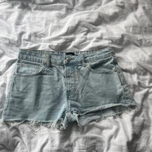 Ljusblå jeansshorts från 157 - Snygga ljusblå jeansshorts från 157 med råa, fransiga kanter och klassisk femficksmodell. Midjemått ca 40cm