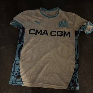 Marseille fotbollströja Puma S - Säljer en vit och ljusblå Olympique de Marseille fotbollströja från Puma. Tröjan är använd 1 gång och kostar 1800kr fast jag säljer den för 899kr