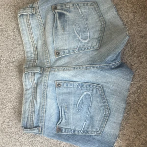 Lågmidjade jeansshorts  - Snygga ljusblå lågmidjade jeansshorts från Esprit med  slitningar för en cool look. Klassisk femficksmodell med broderade bakfickor och detaljer i vitt och rött. Perfekta för sommaren och riktigt sköna att bära till allt.