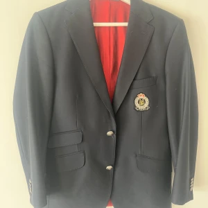 Klassisk marinblå klubbkavaj från Morris – stl. 50 - Säljer en elegant och välsydd klubbkavaj från Morris, storlek 50. Kavajen har en sofistikerad marinblå utsida och en stilren, kontrasterande röd innerfoder som ger den ett exklusivt intryck.