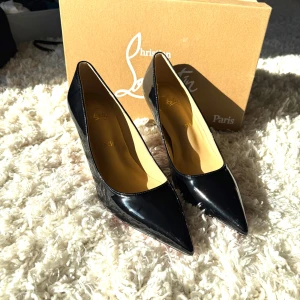 Svarta pumps från Christian Louboutin - Klassiska svarta pumps från Christian Louboutin i lackat skinn med ikonisk röd sula. Skorna har spetsig tå och hög klack, perfekt för dig som vill sticka ut med en elegant och tidlös look. Använt fåtal gånger! 