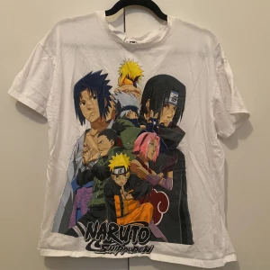 Naruto Shippuden vit t-shirt anime - Vit t-shirt med stort färgglatt Naruto Shippuden-tryck framtill. Motivet visar flera karaktärer från serien i olika poser. Klassisk passform med rund hals och korta ärmar. Perfekt för dig som älskar anime och vill sticka ut med en cool och unik stil.