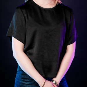 Svart kortärmad blus i satinlook - En stilren svart blus med korta ärmar och rund halsringning. Toppens material har en lätt glansig satinlook som ger en lyxig känsla. Passformen är normal och toppen är enkel att matcha till olika outfits.