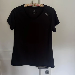 Svart tränings-tshirt North Bend - Svart t-shirt från North Bend med v-ringning och korta ärmar. Perfekt för träning, tillverkad i ett lätt och funktionellt syntetmaterial som andas. Diskret logga på bröstet. Snygg och enkel design som passar till alla sportiga outfits. Kan mötas upp i Norrköping😊