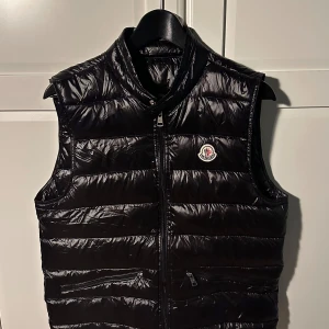 Moncler Gui väst - Hej, säljer en snygg väst från moncler som passar perfekt till kyligare sommarkvällar eller vid lite finare tillfällen. Västen är i mycket bra skick (9/10), västen har storleken 2 vilket är som S/M.  Hör gärna av dig vid eventuella frågor eller för fler bilder. 