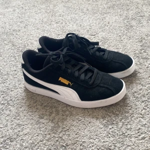 Svarta Puma sneakers i mocka, strl 36 - Snygga svarta Puma sneakers i mocka med vit sula och vit sidodetalj. Klassisk låg modell med snörning och guldfärgad Puma-logga på sidan. Perfekta för en stilren och sportig look.endast andvända en eller två gånger. Priset kan diskuteras. Dom är som nya. Hör av er om ni har frågor. 💗