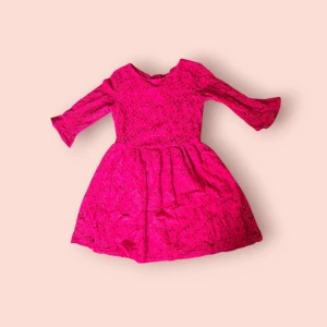 Röd spetsklänning med trekvartsärm - Supersöt rosa kortklänning i spets med blommigt mönster och trekvartsärmar. Klänningen har en markerad midja, v-ringning och dragkedja i ryggen. Perfekt för dig som vill sticka ut med en färgstark look.