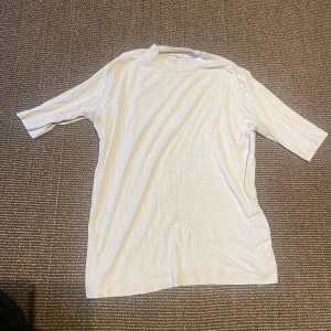 Vit ribbad t-shirt med kort ärm - Snygg vit t-shirt med diskret ribbat mönster och korta ärmar. 