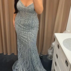 Glittrig blå långklänning med paljetter - Säljer en magisk blå långklänning med glittriga paljetter i ett unikt mönster. Klänningen har en v-ringad urringning och är ärmlös, med en figurnära passform som ger en elegant siluett. Perfekt för bal eller fest där du vill glänsa extra mycket!            Nypris: 7000kr  . Priset kan diskuteras vid snabb affär