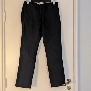 Svarta chinos - Svarta chinos från Burton Menswear London i bomull med stretch. Byxorna har resår och snörning i midjan för extra komfort samt fickor både fram och bak. Perfekta för en clean och avslappnad look. 