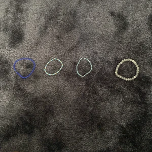 Fyra färgglada pärlarmband - Säljer fyra handgjorda armband med pärlor i olika färger. Ett armband har gråmelerade pärlor, ett är blått och de andra två har små pärlor i blått, gult och vitt. Perfekta för att ge din outfit en personlig touch.