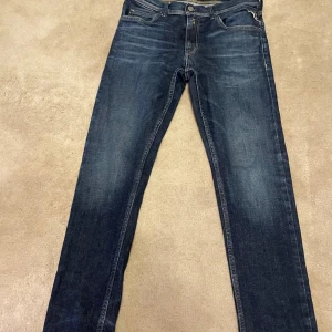 Mörkblå jeans från Replay 158/164cm - Snygga mörkblå jeans från Replay, modell Wallys. Klassisk femficksdesign med kontrastsömmar och cool detalj på bakfickan. Jeansen har rak passform och är tillverkade i slitstarkt denimtyg. Perfekta för dig som gillar stilrena och tidlösa jeans.