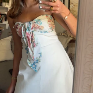 Vit axelbandslös klänning med blommor - Klänning från Zara i stl XS som passar perfekt  till sommaren, skriv gärna för fler bilder eller vid intresse💗 Endast använd en gång