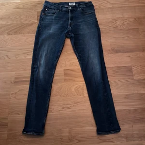 Mörkblåa jeans från Tiger of Sweden - Säljer ett par mörkblå jeans från Tiger of Sweden. Jeansen har en straight  passform och är tillverkade i mjukt denimtyg. Jeansen är nästan i nyskick men på ett ställe är tyget lite slitet men som knappast märks av. Perfekta för dig som gillar en stilren och modern look. Om du har någon fundering är det bara att fråga🙌😀