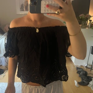 Svart offshoulder blus med broderi - Supersöt svart offshoulder blus med broderade detaljer och hålmönster längs ärmar och nederkant. Croppad modell med vida, korta ärmar. Storlek M men passar mer en xs/s