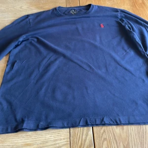 Marinblå långärmad tröja från Polo Ralph Lauren – Storlek S - En klassisk och stilren marinblå långärmad tröja från Polo Ralph Lauren i storlek S. Tillverkad i mjukt och bekvämt material, perfekt för svalare dagar. Plagget är i mycket bra skick och ett tidlöst tillskott i garderoben.