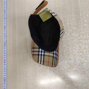 Burberry keps - Snygg keps från Burberry med klassiskt beige, svart, vit och röd rutigt mönster. Justerbar rem baktill i läderlook och böjd skärm. Perfekt accessoar för en trendig streetstyle. Tillverkad i bomull för en bekväm känsla. Helt oanvänd