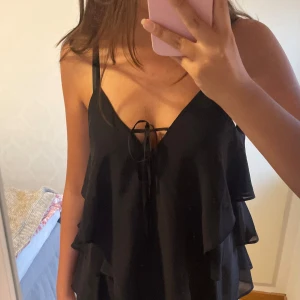 Svart volangig linnetopp med knyt - Svart linnetopp med volanger från Vero Moda i XS men är luftig så passar S-M. Mycket bra skick💕