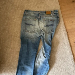 Blå Nudie Jeans straight fit - Säljer ett par klassiska blå jeans från Nudie Jeans med snygga slitningar. Storleken är 32&32. Jeansen är i väldigt bra skick och passar perfekt till det mesta. Nypris:1700, mitt pris: 549
