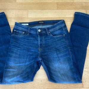 Jack & Jones jeans - Tjena, nu säljer jag dessa riktigt feta mörkblå Slim Glenn jeans från Jack & Jones på grund av att de var lite för stora för mig så de är aldrig använda. Så skick 10/10. De har en klassisk femficksdesign och snygga kontrastsömmar. Jeansen har slim fit-passform. Ifall ni har frågor eller funderingar så är det bara att skriva så svarar jag så snabbt jag kan.      Mvh Moses