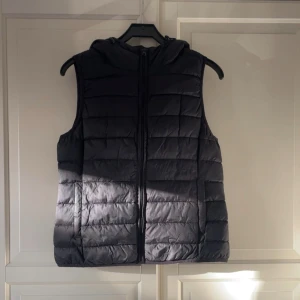 Svart dunväst med luva från ONLY - Svart quiltad dunväst från ONLY i storlek L. Västen har en praktisk huva, dragkedja framtill och en stilren design. Knappt använd. Skriv om du har några funderingar💕💕