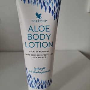 Forever Aloe Body Lotion 236 ml - Aloe Body Lotion från Forever med aloe vera, niacinamid, hyaluronsyra och oljor från argan, jojoba och macadamianöt. Lätt och snabbt absorberande formula som återfuktar och stärker hudens skyddsbarriär. Kommer i en vit tub med blå detaljer, 236 ml.