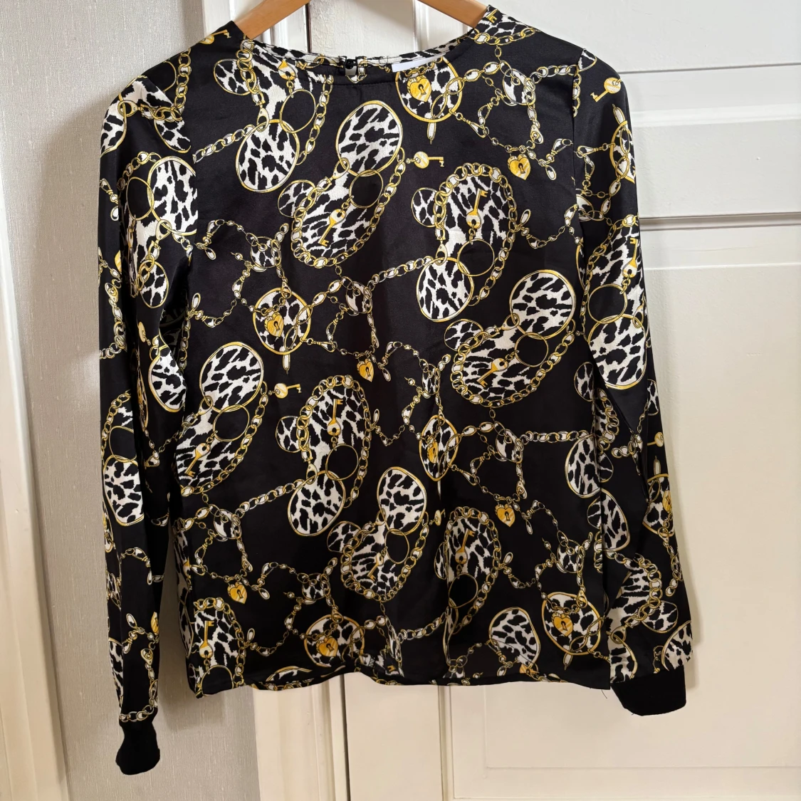 Svart blus med kedje- och leopardmönster