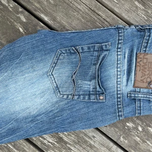 Lågmidjade jeans - Snygga blå jeans från Broadway NYC med slitna detaljer och klassisk femficksmodell. Jeansen har  normal passform och coola kontrastsömmar. Tillverkade i bomull med en tvättad look som ger en avslappnad vibe.