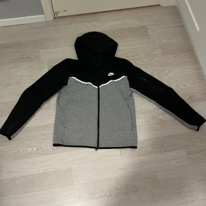 Nike hoodiejacka svart/grå M - Nike tech hoodie svart/grå använder den inte längre så tar bara plats i garderoben så tänkte se om någon annan har bättre användning av tröjan än mig storlek m, mycket bra skick    