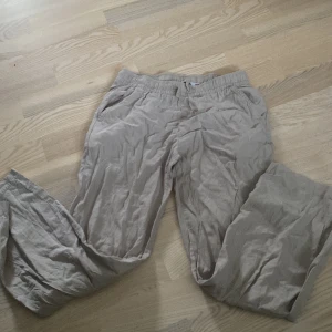 Beiga linnebyxor från 157 - Snygga beiga linnebyxor från 157 med resår i midjan och raka ben. Byxorna har sidfickor och en bakficka, perfekta för en chill och avslappnad stil. Lätta och luftiga i materialet, passar grymt till sommaren.