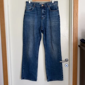 Blå raka jeans från JDY Only  - Klassiska blå jeans från JDY med raka ben och hög midja. Jeansen har fem fickor, bälteshällor och stängs med knapp och dragkedja. Materialet är robust denim i bomull och passformen är normal med en snygg vintage tvätt.