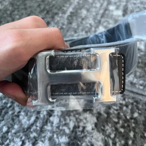 Svart bälte med H - H silver buckla med svart band. Helt ny o 105cm i storlek. Kom dm för frågor👍🏼