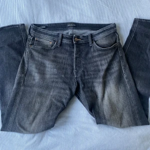Svarta Jack&Jones jeans - Snygga svarta jeans från Jack&Jones i modellen Tapered Erik, storlek 32/34. Passformen är tapered med smalare ben och normal midja. Mycket fina jeans i fint skick. Hör av dig vid intresse😁