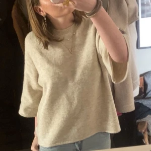 Beige stickad tröja med trekvartsärm - Säljer en beige stickad tröja med rund hals och trekvartsärmar. Tröjan har en loose passform och är perfekt att matcha med jeans eller kjol. Mjuk och skön känsla, enkel att styla med smycken för en chill look.